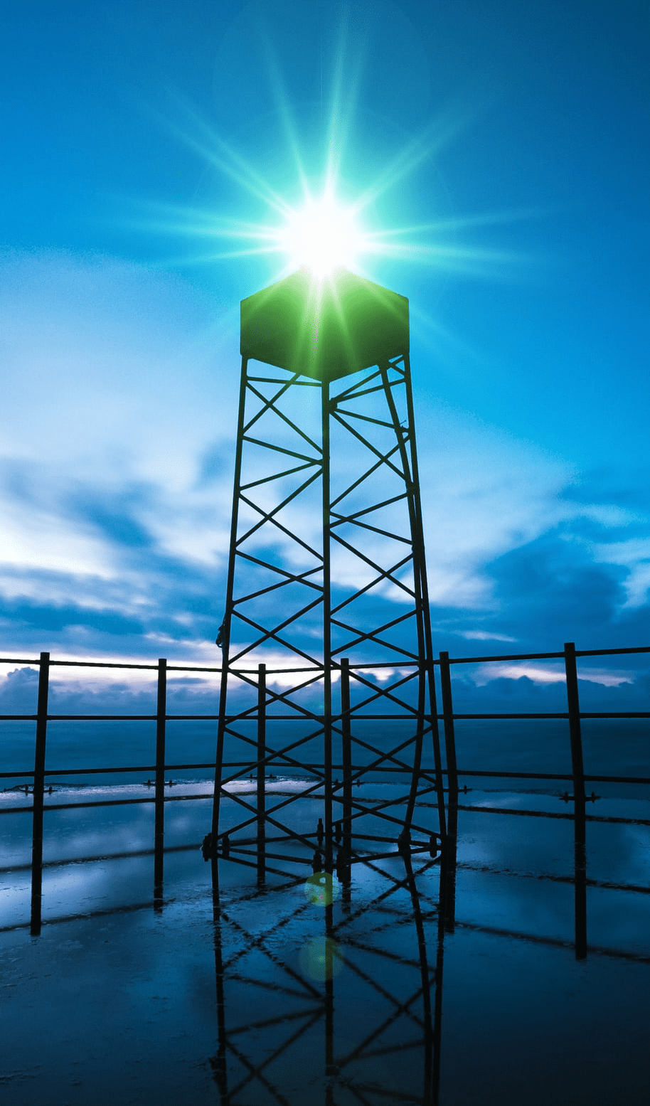 A green light shines on top of a structure in the distance